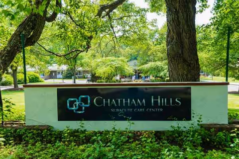 Outdoor sign for Chatham Hills Subacute Care Center among green trees.