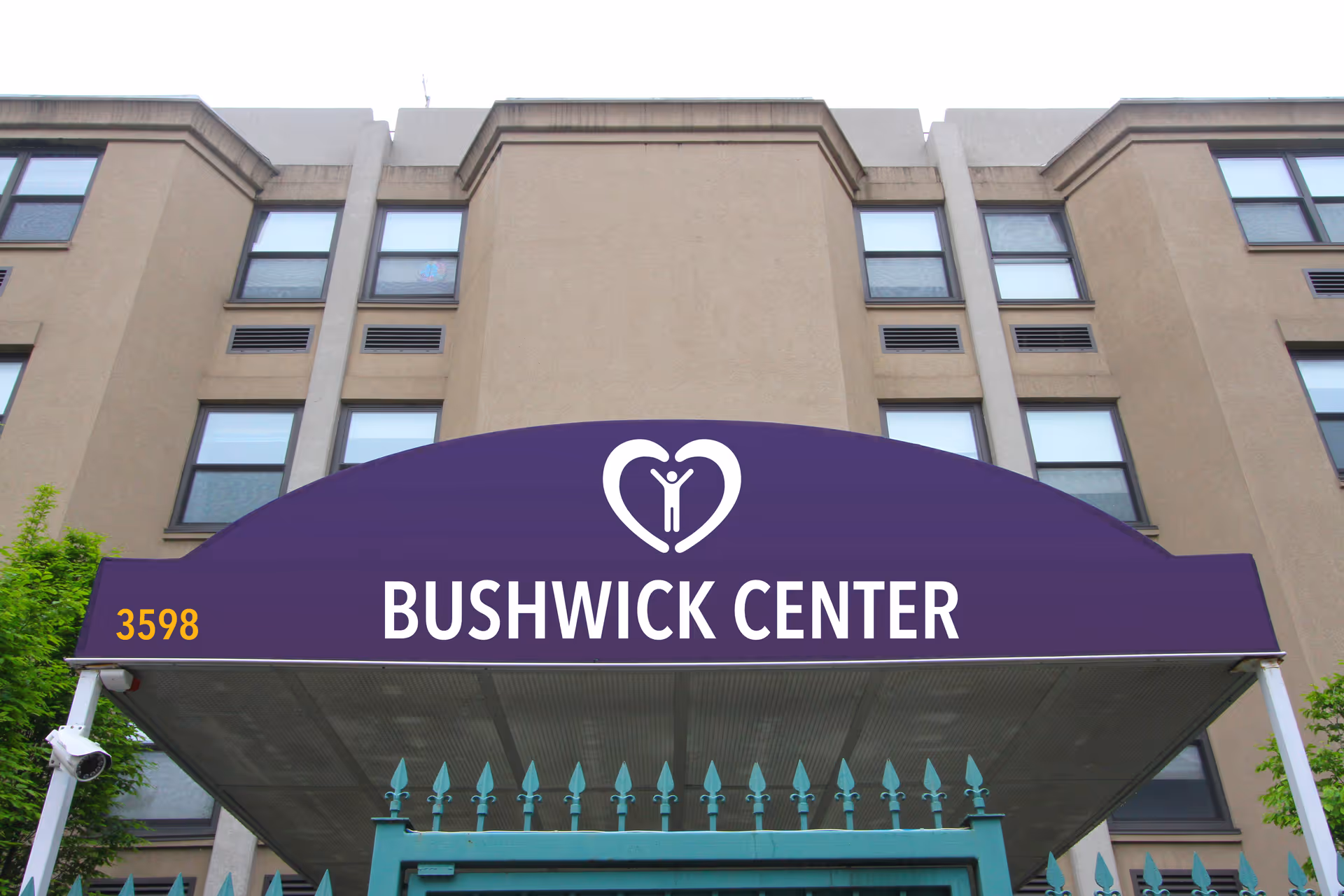 Purple awning that reads 'BUSHWICK CENTER' with the address 3598 over the entrance of a beige multi-story building.