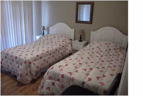 Two twin beds with matching floral quilts, white headboards, and lamps between bedside tables.