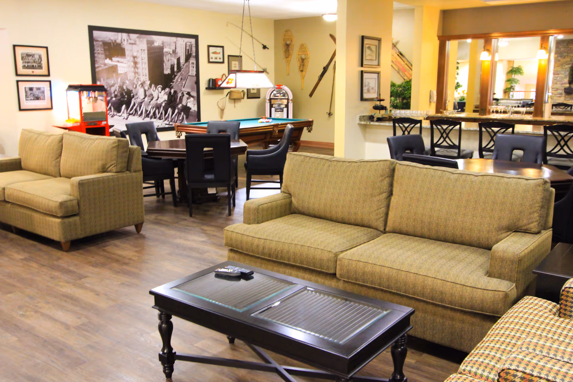 Bright communal lounge with sofas, a coffee table, a pool table, dining chairs and a bar area.