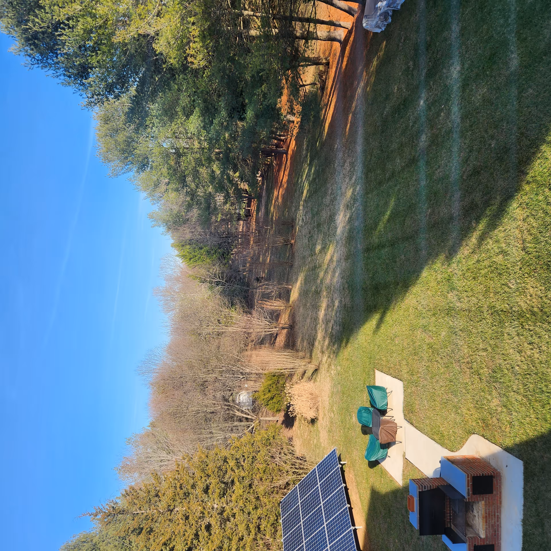 Sunny outdoor area with patio chairs, a brick grill, and solar panels.