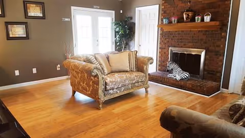 Cozy living room with brick fireplace, patterned sofa, hardwood floors, and decorative accents.
