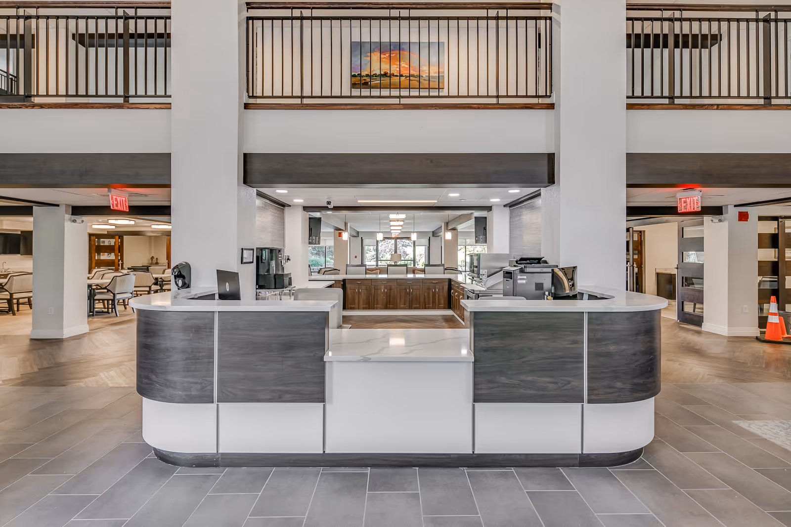 Modern reception desk in a spacious lobby with seating and an upper balcony.