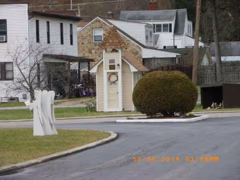 Exterior view of Nella's facility with a small front entrance, shrubs, driveway, and surrounding houses.