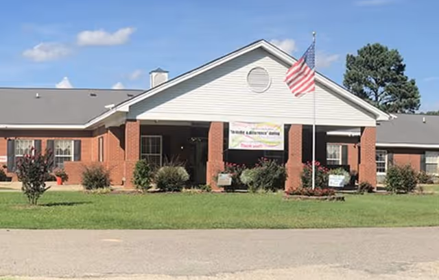 Exterior view of Cesca Adult Care Home with brick entrance, flagpole, and manicured lawn.