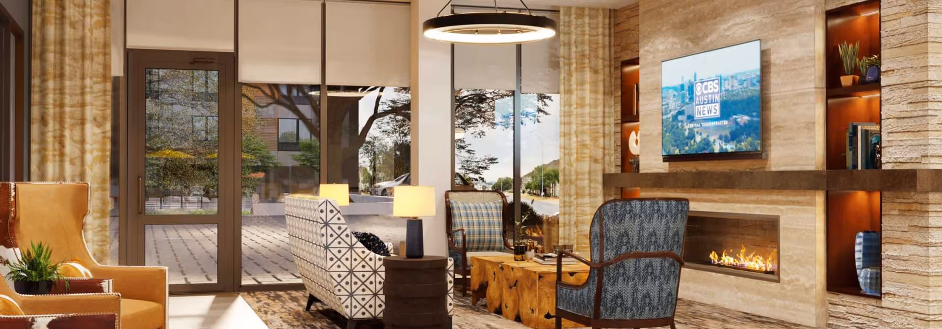 Bright, modern lounge with armchairs and sofas arranged around a fireplace and wall-mounted TV, with large windows and doors overlooking an outdoor courtyard.