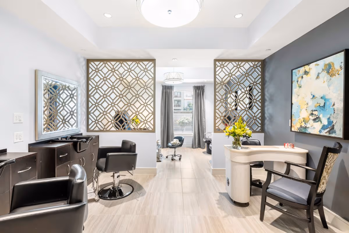 Bright, modern salon area with styling chairs, a manicure desk, decorative room dividers, and artwork.
