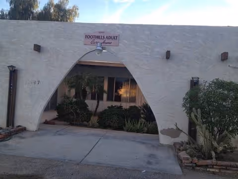 White stucco building with an arched entry and Foothills Adult Care Home sign