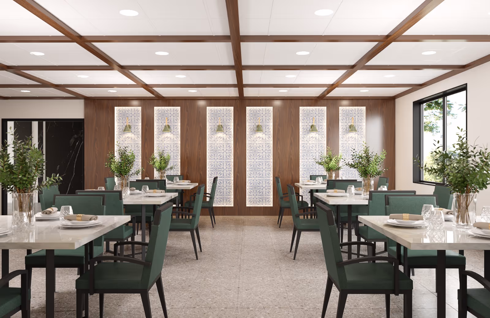A modern dining room with multiple tables set with plates, glasses, and napkins. Each table has green cushioned chairs and a vase with green leafy plants. The room features a wooden accent wall with decorative panels and pendant lights, a tiled floor, and a large window letting in natural light.