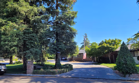 Front exterior of a senior living facility with a circular driveway and trees.