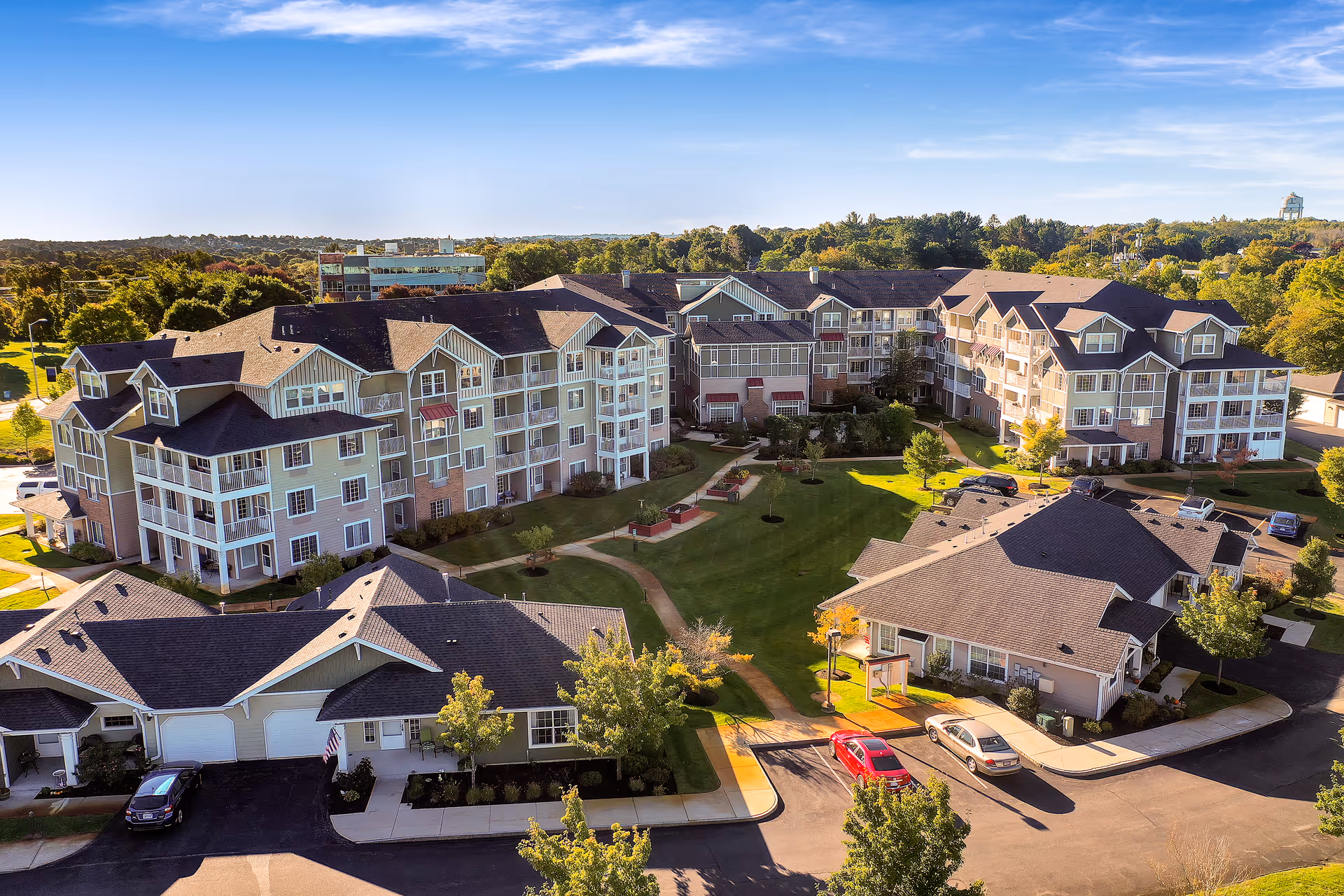 Aerial view of a multi-building senior living community with landscaped courtyards, walkways, and parking areas.