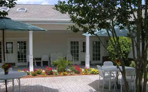Outdoor patio with white chairs and tables, umbrellas, and a building entrance.