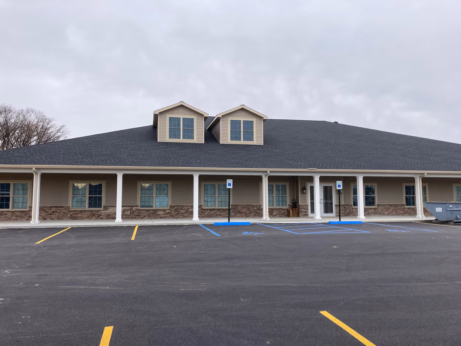 Single story assisted living facility with a long covered front porch and parking area.