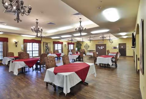 Spacious dining hall with round tables covered in red and white cloths and chandeliers.