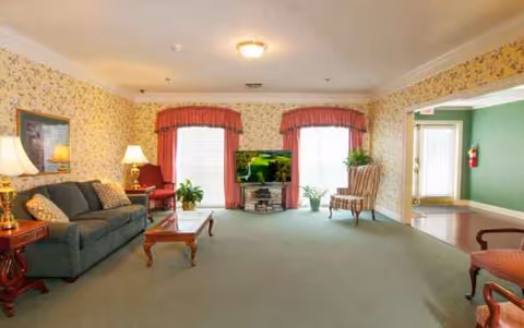 Cozy living room at Magnolia Estates of Oconee with sofa, chairs, TV, and plants.