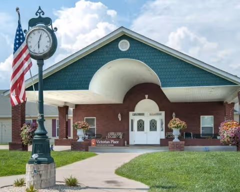Front exterior of Victorian Place of St. Clair with clock, flag, and entrance.