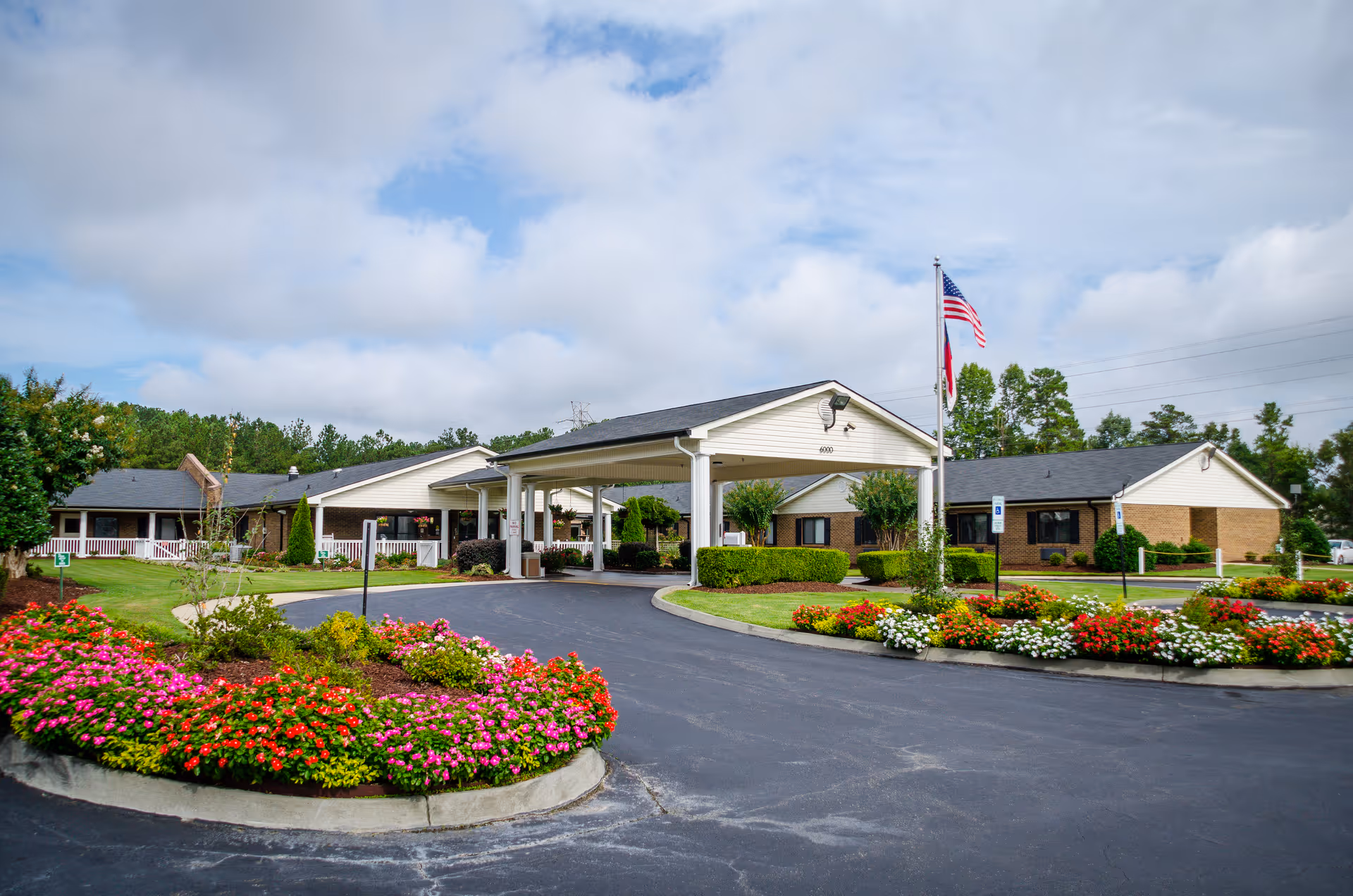 Exterior view of a single-story senior living facility with a front entrance and landscaped grounds.