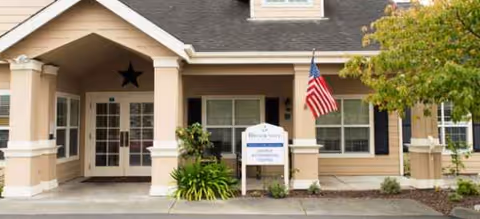Front entrance of Sequoia Springs Senior Living Community with flag, pillars, star decor, and signage.
