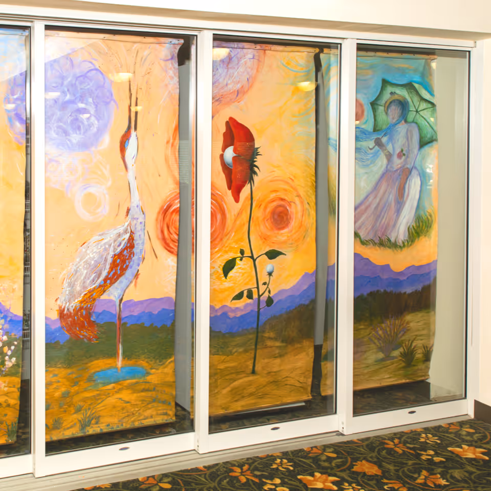 Colorful painted glass panels showing a crane, a large flower, and a woman with an umbrella displayed on sliding interior doors.