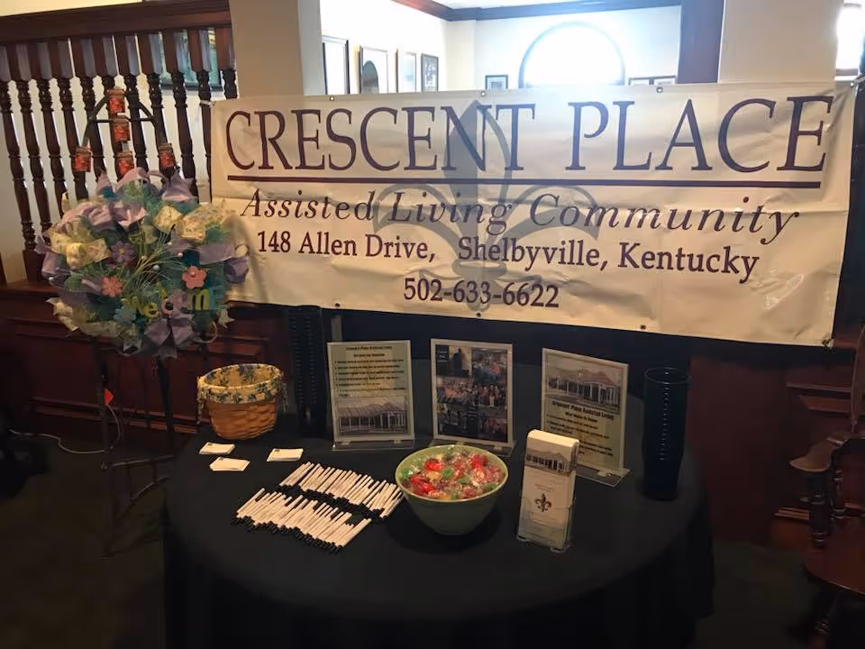 Indoor lobby display with a Crescent Place banner and a table of materials.