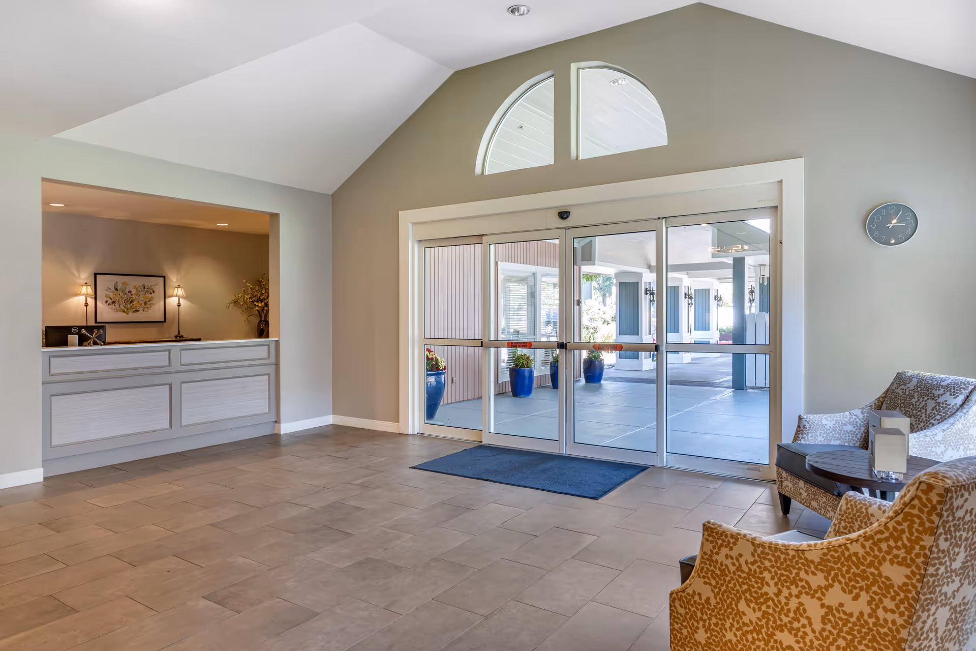 Lobby with sliding glass entry doors, a front desk on the left, and seating area on the right.