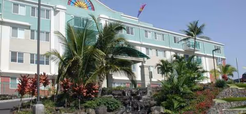 Exterior of Regency at Hualalai, pastel multi-story senior living building with palm trees