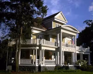 A Victorian-style mansion with a large front porch and columns.