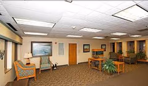Indoor lounge area with beige seating, tables, lamps, and potted plants.