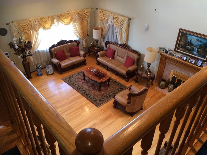 Spacious living room with leather sofas, warm lamps, rug, and fireplace, viewed from a staircase.