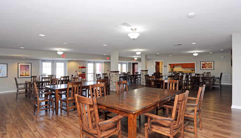 Spacious communal dining area with multiple wooden tables and chairs on hardwood floors.