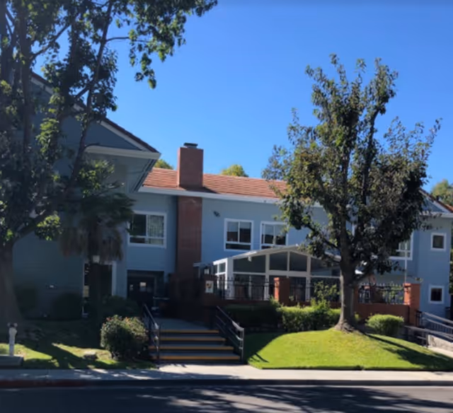 Blue two-story memory care building with brick accents and a front staircase.