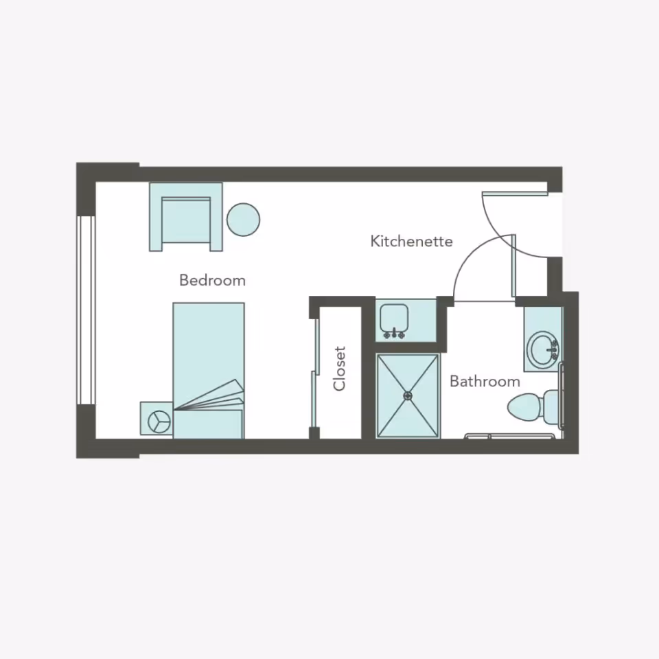 Floor plan of a small living space at Aegis Living Ballard showing a bedroom with a bed, chair, and side table, a kitchenette area, a closet, and a bathroom with a shower, sink, and toilet.