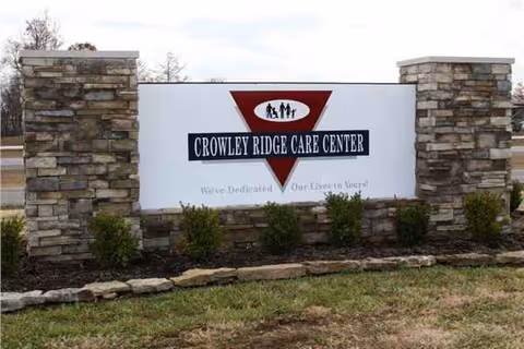 Exterior stone sign reads Crowley Ridge Care Center with surrounding shrubs.