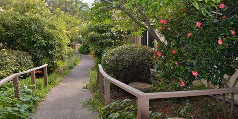 Outdoor garden path at Chaparral House with green shrubs and pink flowering bushes.