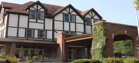 Brookdale Oakwood exterior with Tudor-style, brick entrance and landscaped front courtyard.