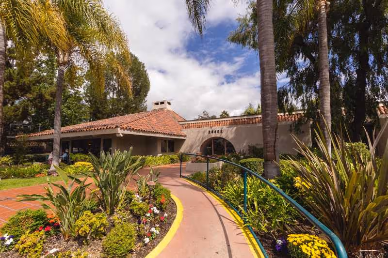 Sunny exterior view of Laguna Hills Health and Rehabilitation Center with a landscaped walkway.