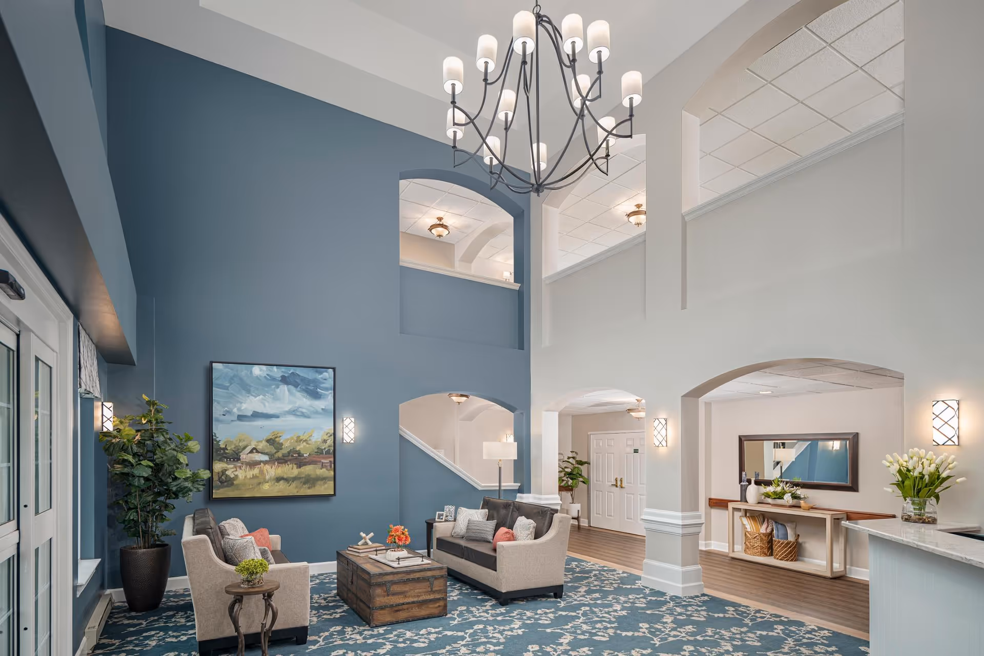 Spacious senior living lobby with a seating area, high ceilings, chandelier, and blue accent wall.