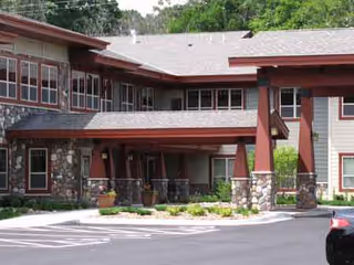Exterior view of Trails of Orono Assisted Living entrance with stone pillars and red beams.