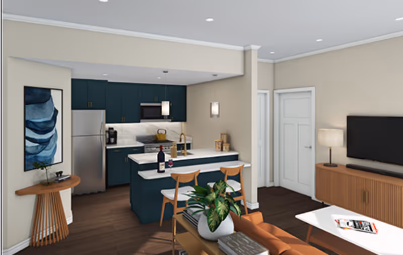 Open-plan interior showing a teal kitchen with an island and bar stools opening into a living area with a sofa and wall-mounted TV.