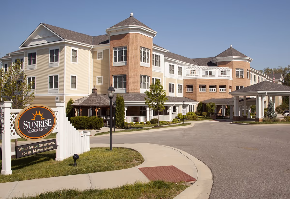Front exterior of the Sunrise of Louisville senior living building with a circular driveway and a large Sunrise Senior Living sign.