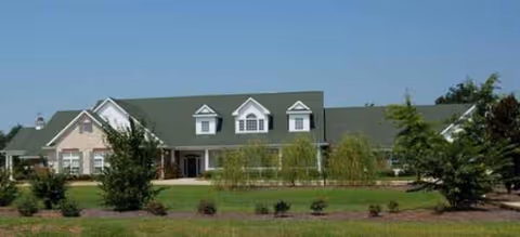 A single-story senior living facility with a green roof and manicured front lawn.
