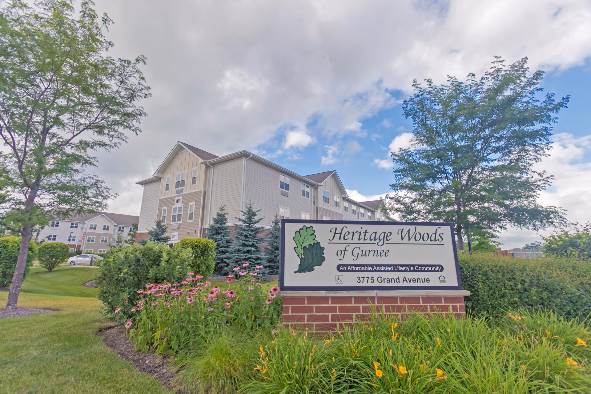 Sign for Heritage Woods of Gurnee in front of the assisted living building and landscaped grounds.