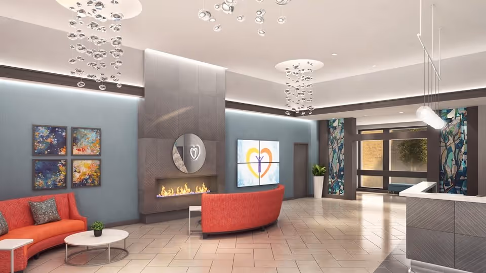 Modern reception lobby with curved red sofas, a fireplace, decorative hanging lights, artwork, and a reception desk.