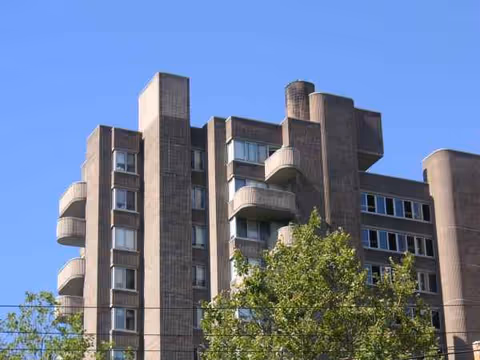 Exterior view of a multi-story concrete building with balconies against a blue sky