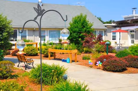 Exterior garden courtyard at Sterling Village with benches and colorful plants.