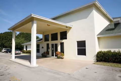 Front view of The Broadmoor ALF, a white senior living facility with covered entrance.