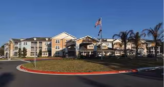 Exterior view of Salishan Gracious Retirement Living, a multi-building senior community with palm trees.