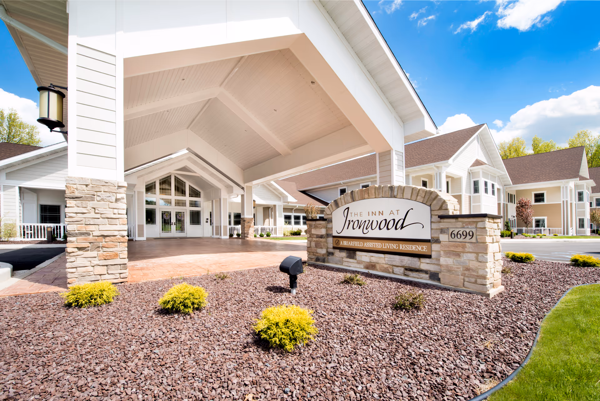 Covered entrance and porte-cochere of The Inn at Ironwood with a stone sign and landscaped rock beds in the foreground.