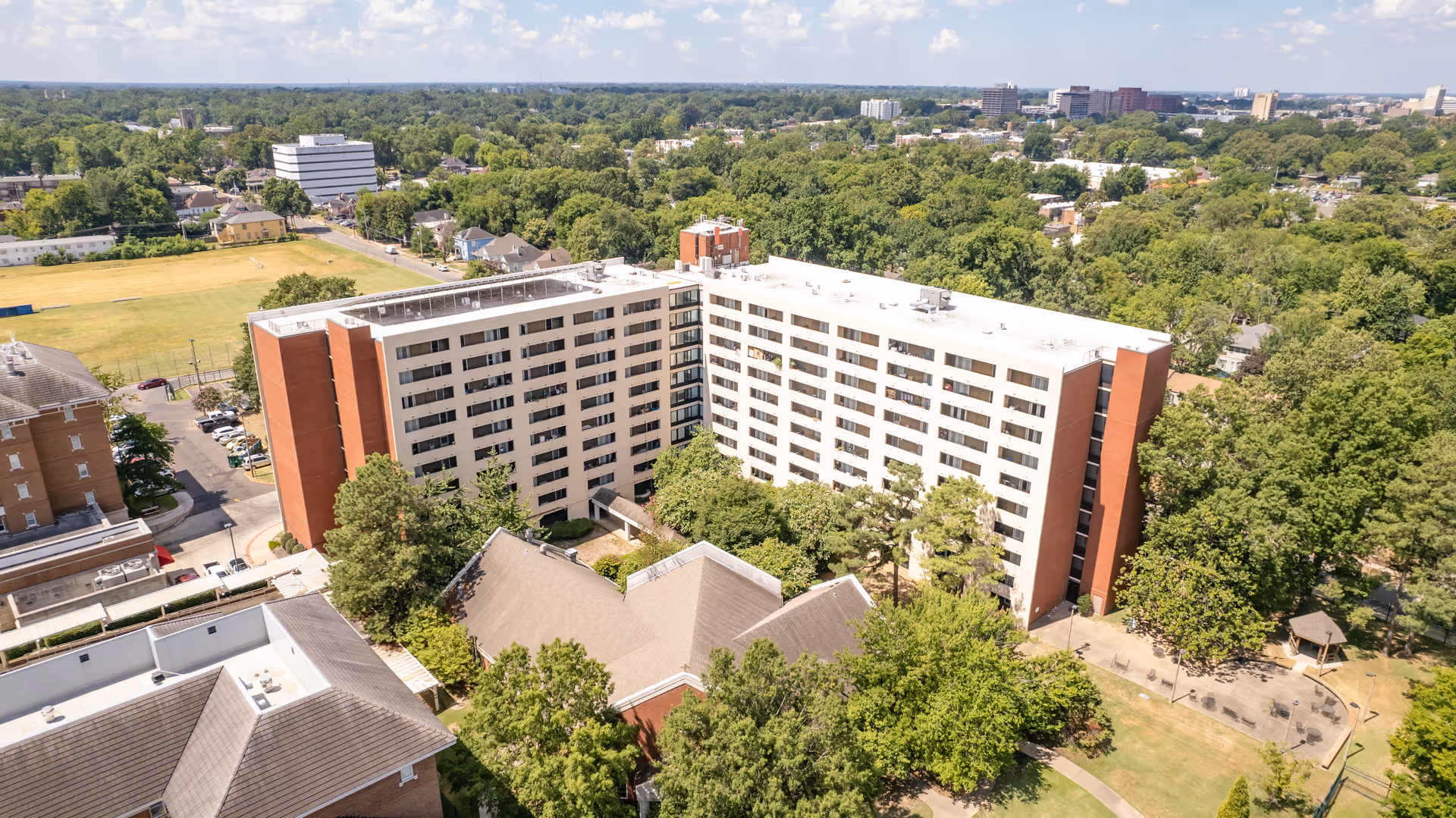 An aerial view of a large, L-shaped senior living facility surrounded by trees.