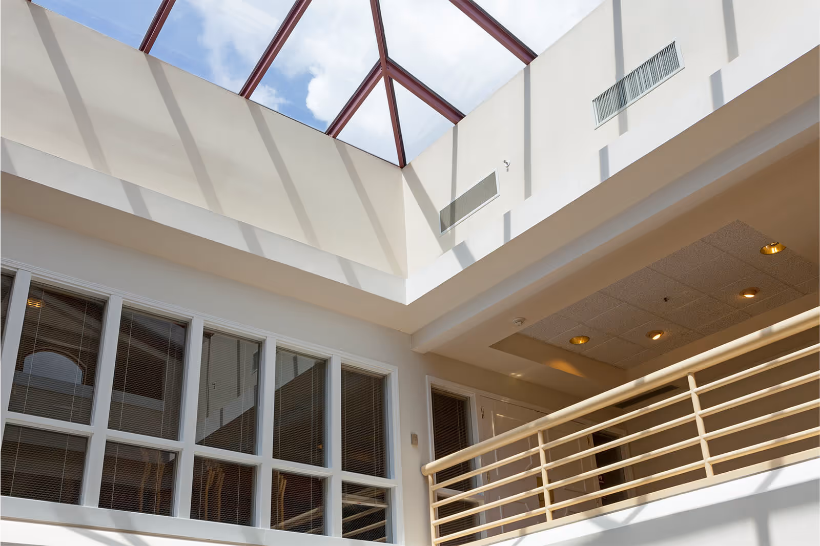 Interior atrium with a large skylight, upper balcony railing, and windows overlooking the space.